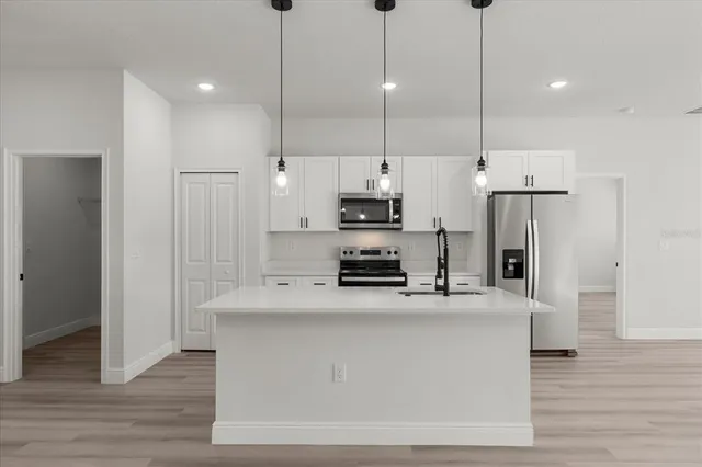 a kitchen with stainless steel appliances granite countertop a refrigerator a stove a sink and a wooden floors