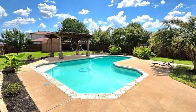 a view of a swimming pool with a patio and a yard