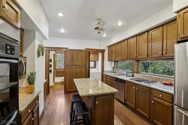 a kitchen with stainless steel appliances granite countertop sink stove refrigerator dining table and chairs