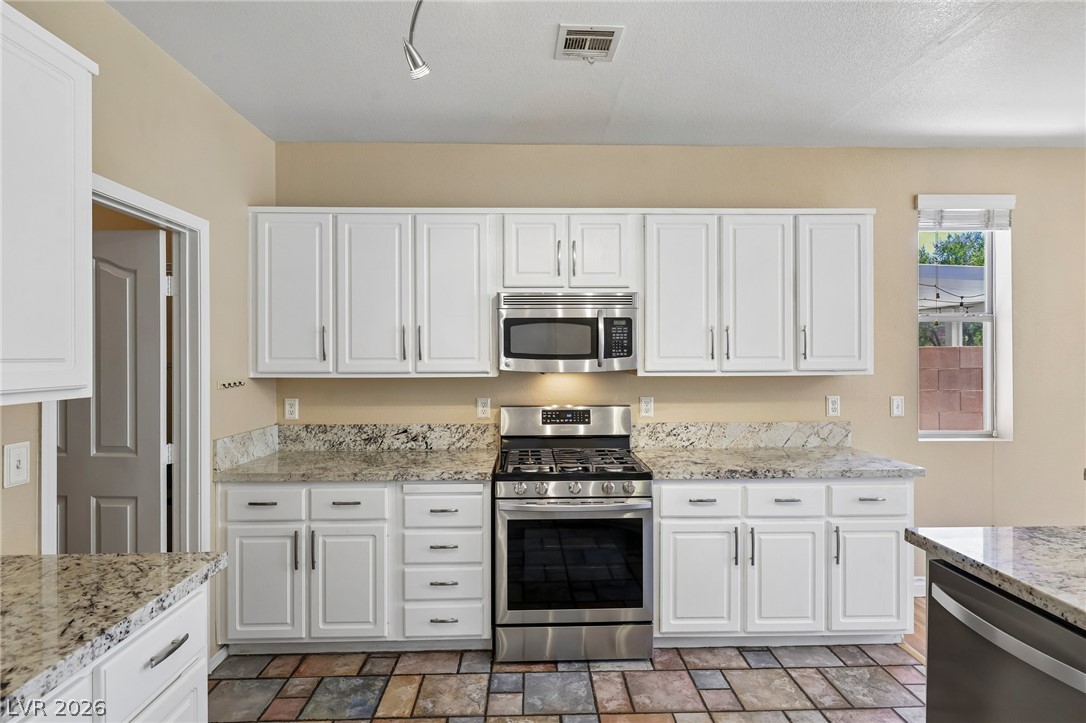 1727 Millstream Way Henderson, NV 89074 - Photo 17 of 46 Bright white cabinetry and patterned tile floors create a welcoming culinary space.