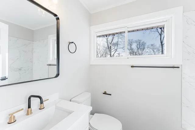 a bathroom with a toilet a sink and mirror