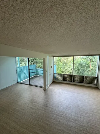 an empty room with large windows and view of balcony