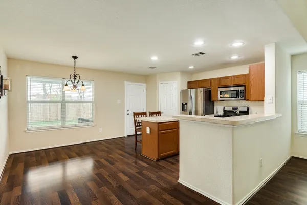 a kitchen with stainless steel appliances granite countertop a refrigerator a stove top oven a sink dishwasher and wooden floor