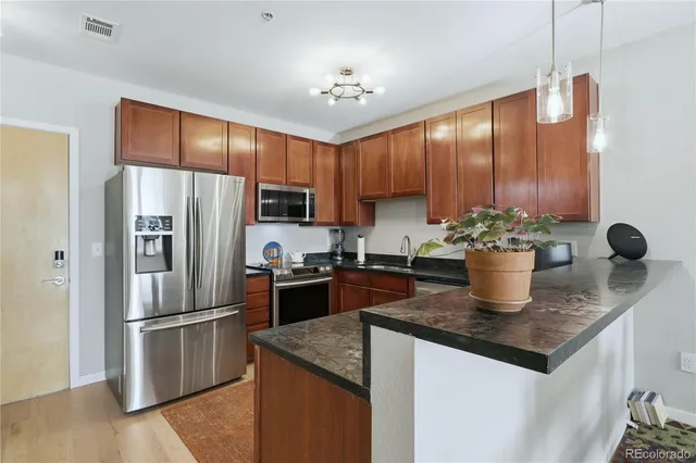 a kitchen with stainless steel appliances granite countertop a refrigerator a stove a sink and dishwasher