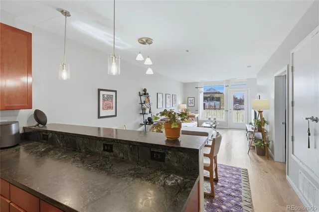 a large living room with stainless steel appliances kitchen island granite countertop a table chairs in it and a wooden floors