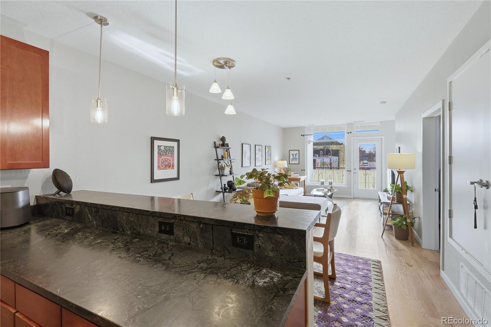 3101 Blake Street, Unit 201 Denver, CO 80205 - Photo 11 of 29 a large living room with stainless steel appliances kitchen island granite countertop a table chairs in it and a wooden floors