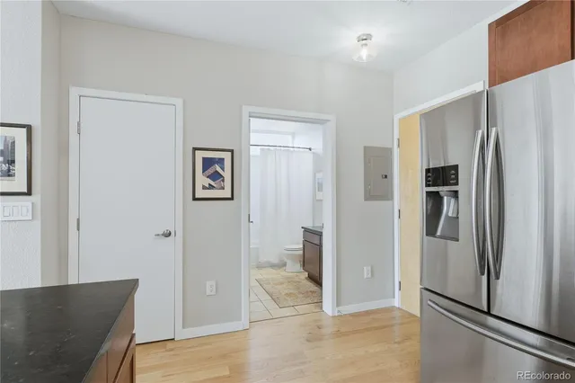 a view of a refrigerator in kitchen and an empty room