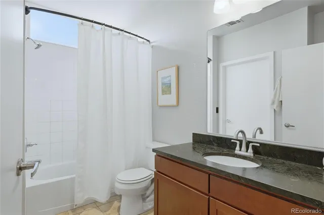 a bathroom with a granite countertop sink toilet and a mirror
