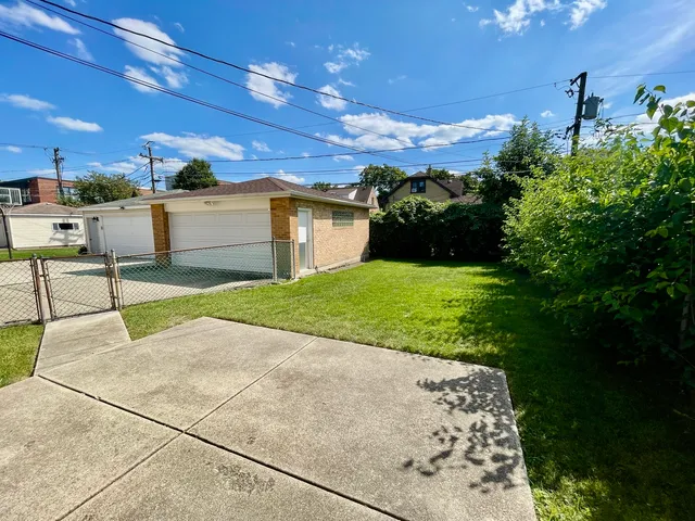 a backyard of a house with plants and large tree