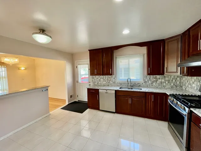a large kitchen with granite countertop a stove sink and cabinets