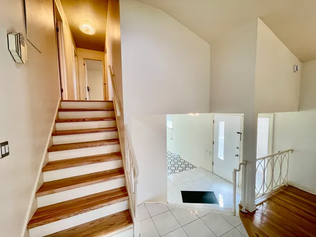 a view of an empty room with chandelier fan and wooden floor