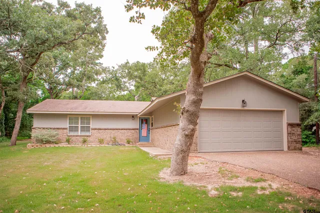 a front view of house with yard and trees in the background