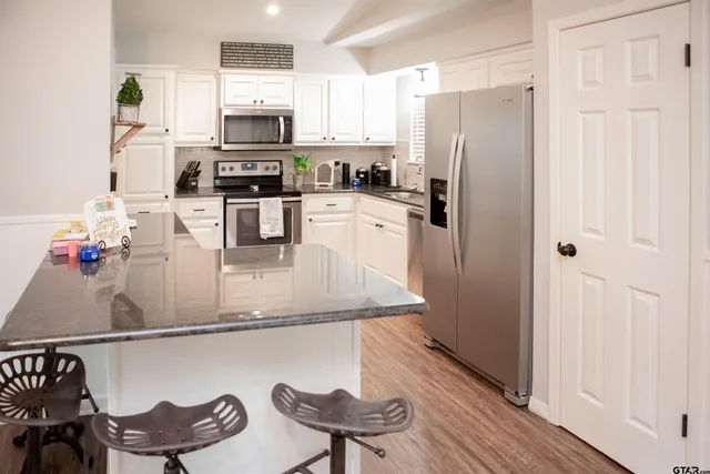 a kitchen with stainless steel appliances granite countertop a refrigerator and a stove top oven