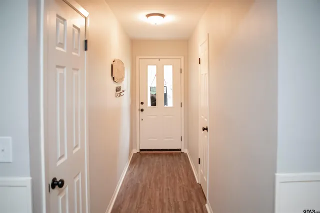 a view of a hallway with wooden floor and a bathroom