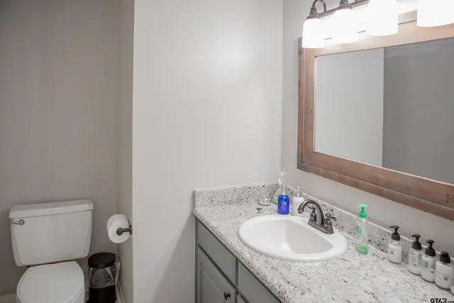 a bathroom with a granite countertop sink toilet and a mirror