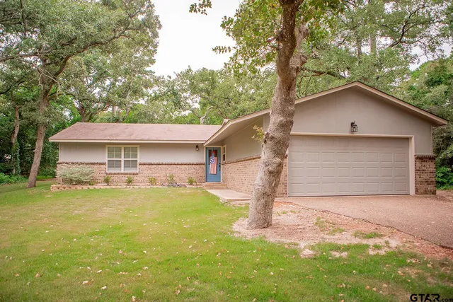 a view of a house with a yard and large tree