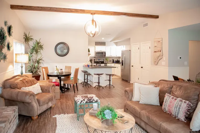 a living room with furniture kitchen view and a chandelier