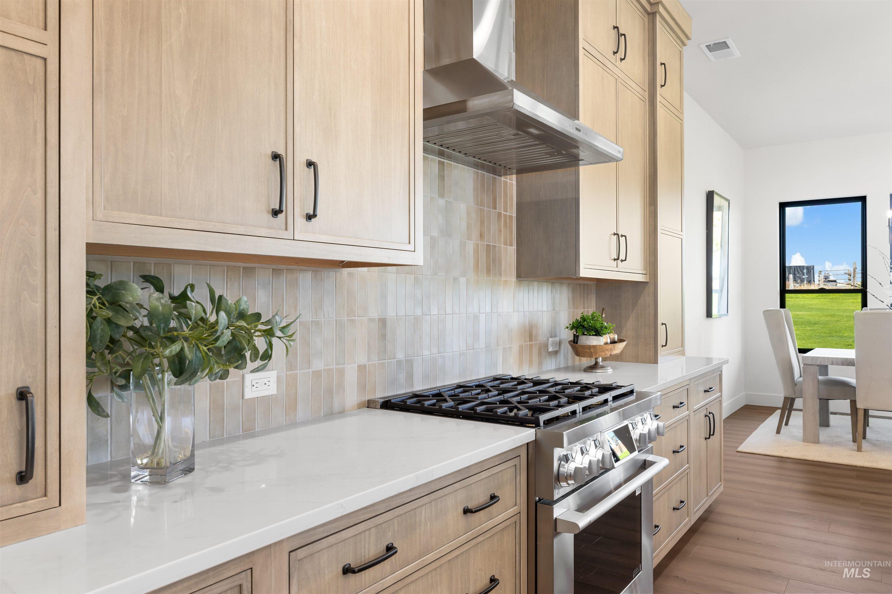 25403 Bur Oak Place Caldwell, ID 83607 - Photo 14 of 46 Kitchen featuring gas range, wall chimney range hood, tasteful backsplash, light stone countertops, and wood finished floors