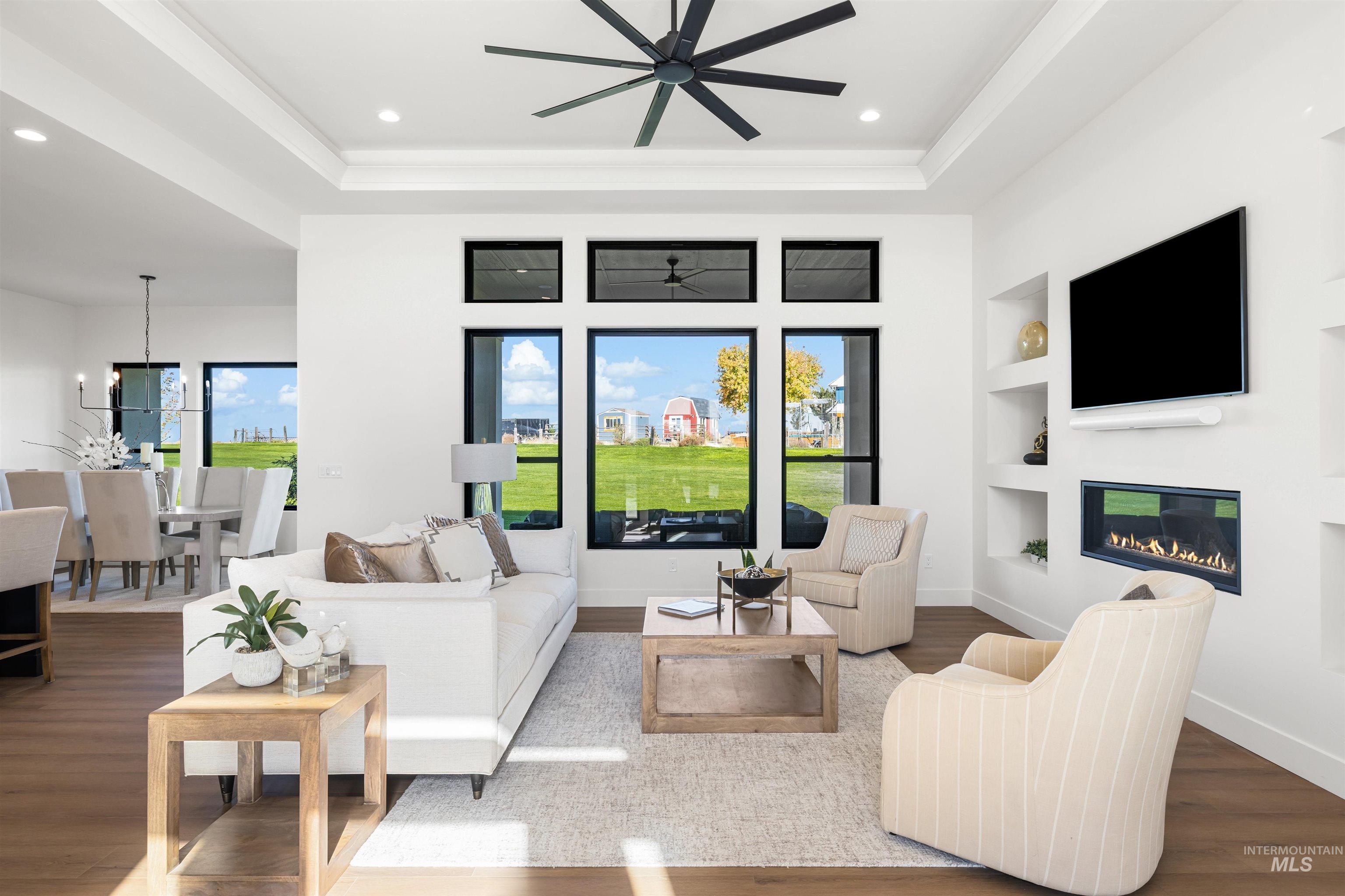 25403 Bur Oak Place Caldwell, ID 83607 - Photo 5 of 46 Living area with wood finished floors, recessed lighting, built in features, a glass covered fireplace, and a raised ceiling