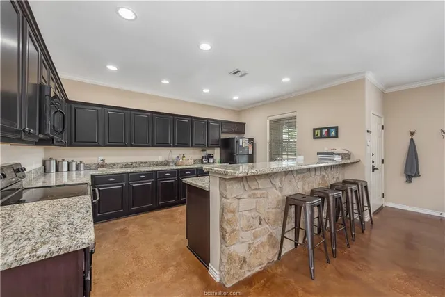 a kitchen with stainless steel appliances granite countertop a stove top oven a sink dishwasher and a refrigerator with wooden floor