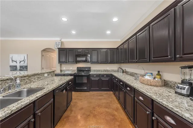 a large kitchen with stainless steel appliances granite countertop a sink stove and cabinets