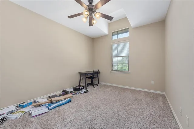 an empty room with windows and ceiling fan
