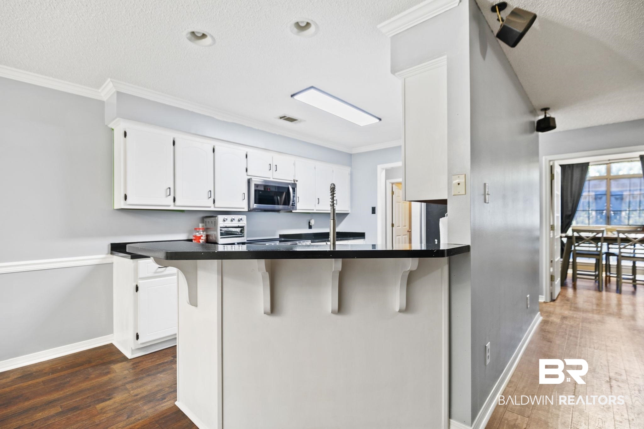 10550 Patrick Avenue Grand Bay, AL 36541 - Photo 15 of 43 Kitchen with white cabinetry, a kitchen breakfast bar, dark hardwood / wood-style flooring, and kitchen peninsula