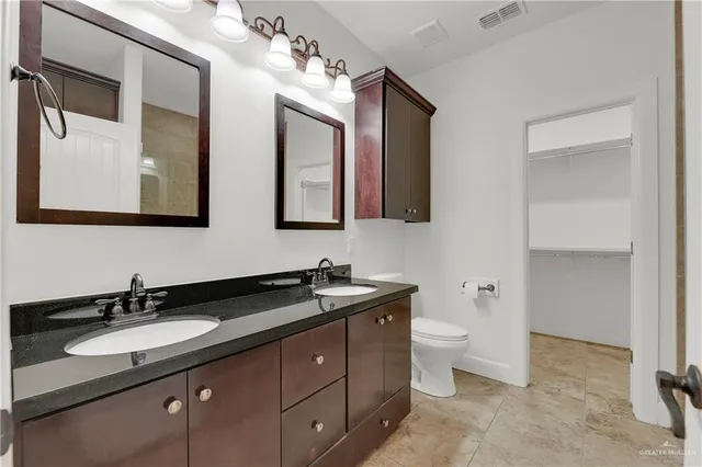 a bathroom with a toilet sink double vanity and mirror