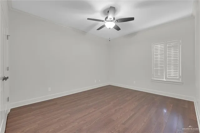 an empty room with wooden floor ceiling fan and windows