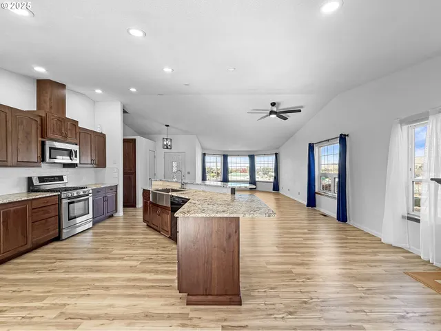 a room with stainless steel appliances kitchen island granite countertop a stove and cabinets