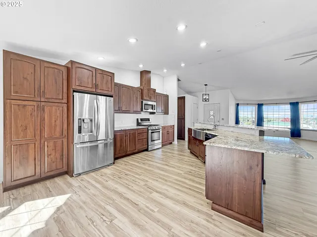 a kitchen with stainless steel appliances granite countertop a refrigerator oven a sink dishwasher and white cabinets with wooden floor