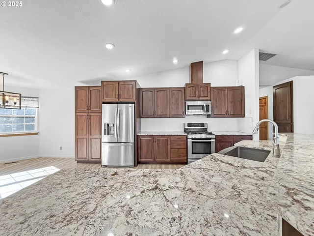 a kitchen with stainless steel appliances granite countertop a stove refrigerator and cabinets