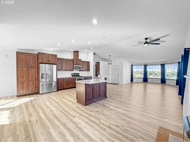 a large kitchen with stainless steel appliances kitchen island a large counter top and a wooden floors
