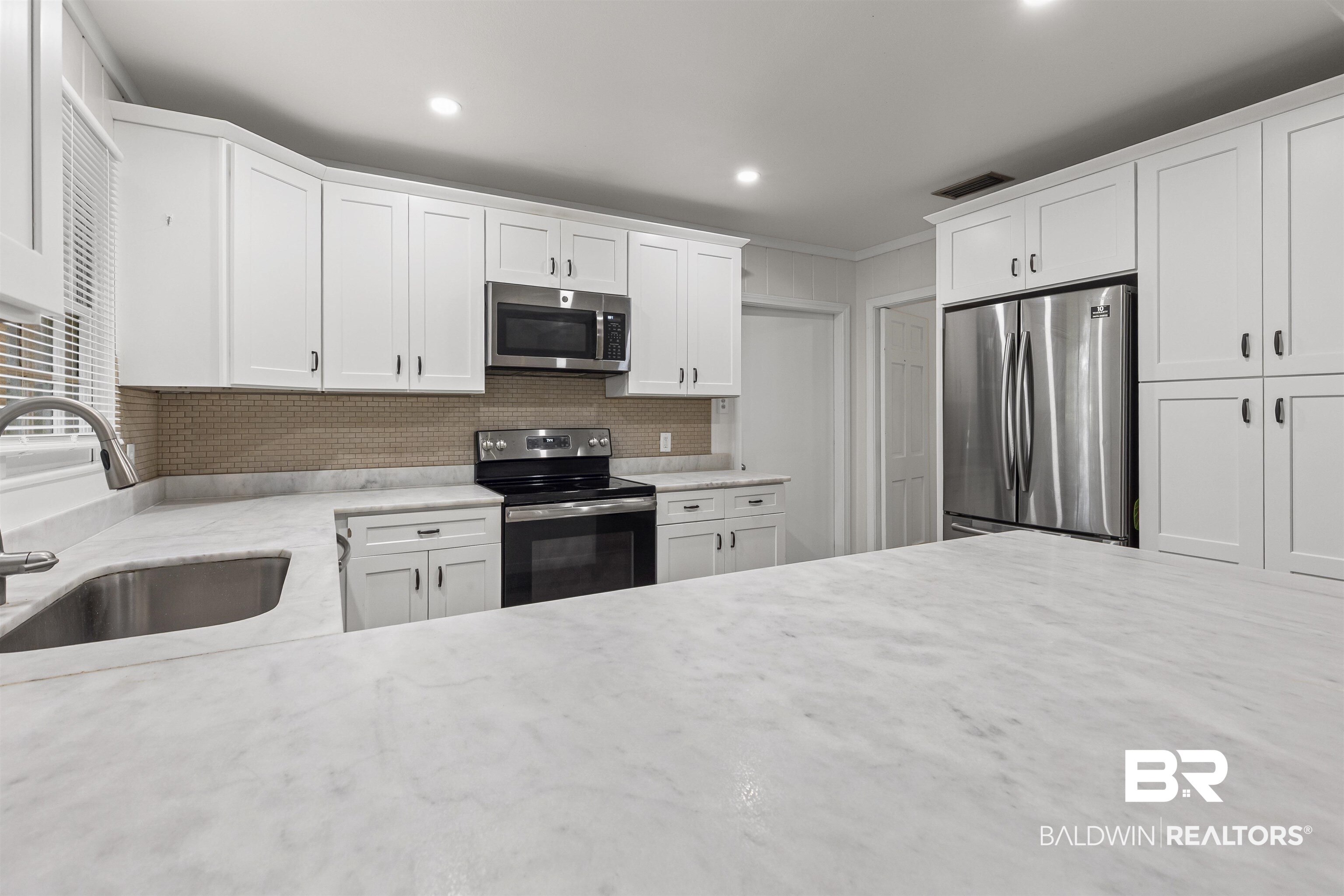 1108 Locarno Street Mobile, AL 36608 - Photo 9 of 24 Kitchen with stainless steel appliances, white cabinets, light stone countertops, crown molding, and backsplash