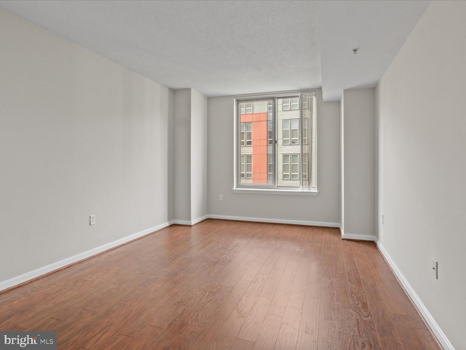 2726 Gallows Road, Unit 411 Vienna, VA 22180 - Photo 10 of 36 a view of an empty room with wooden floor and a window