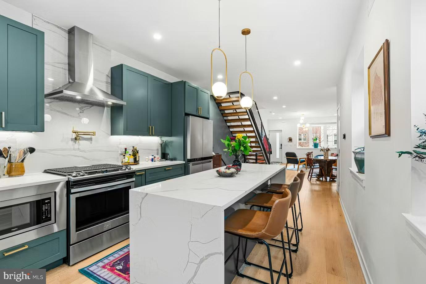 936 Tasker Street Philadelphia, PA 19148 - Photo 4 of 17 a kitchen with stainless steel appliances a stove a sink a oven a dining table and chairs with wooden floor