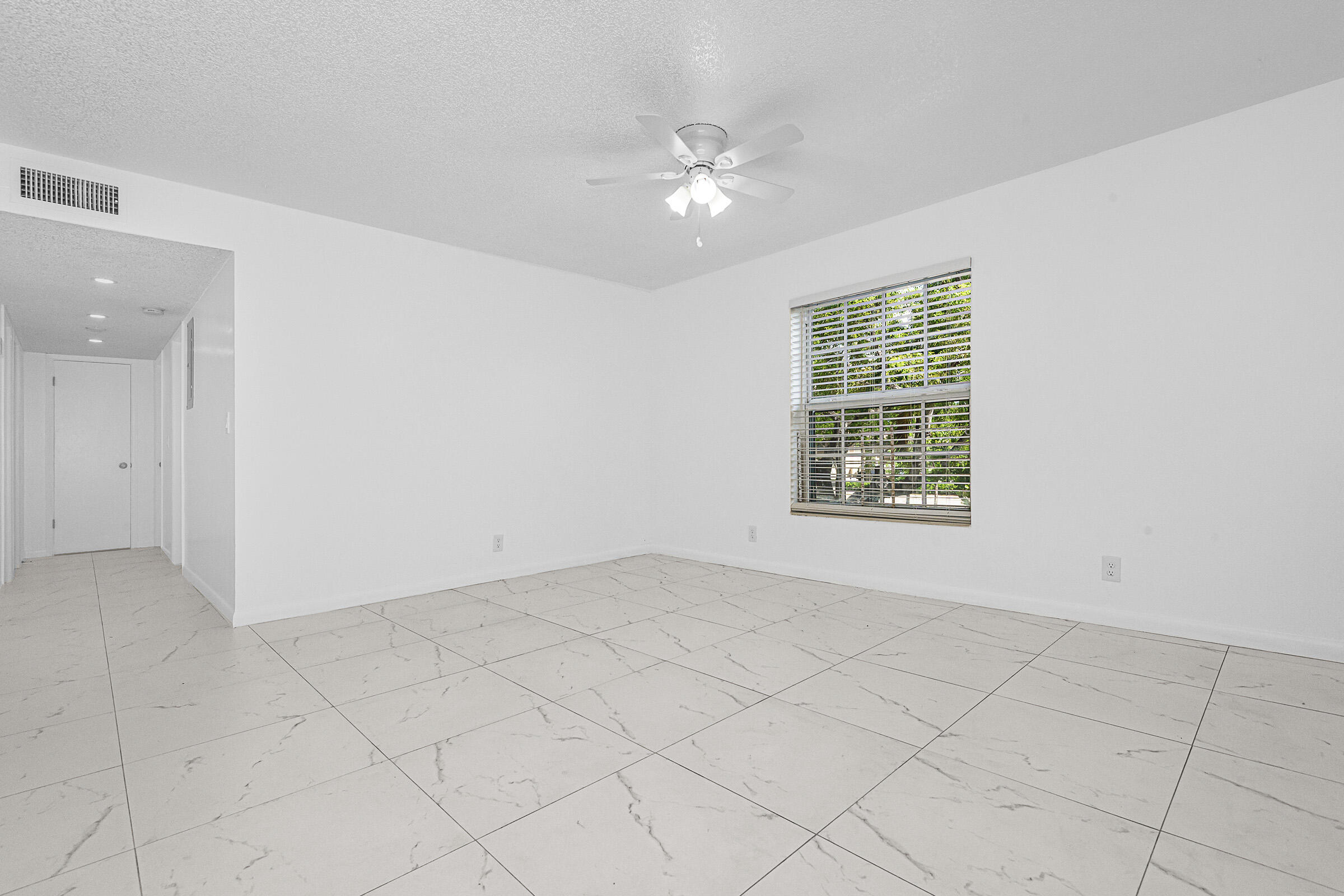 8706 West Sample Road, Unit 4 Coral Springs, FL 33065 - Photo 7 of 21 an empty room with windows and chandelier fan