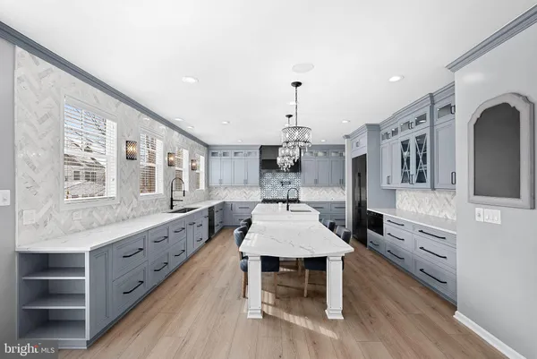 a large kitchen with kitchen island a stove a refrigerator a sink dishwasher and a dining table with wooden floor