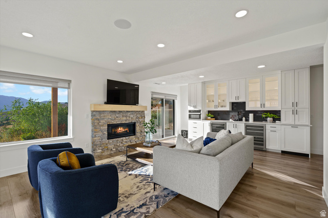 4499 North Seven Bridges Road, Unit 9 Eden, UT 84310 - Photo 32 of 65 Recessed lighting, wood-finish flooring, stone-clad fireplace with a wood mantel, built-in cabinetry with glass-front uppers, and integrated beverage refrigerators