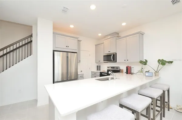 a kitchen with stainless steel appliances a sink a microwave a refrigerator and cabinets