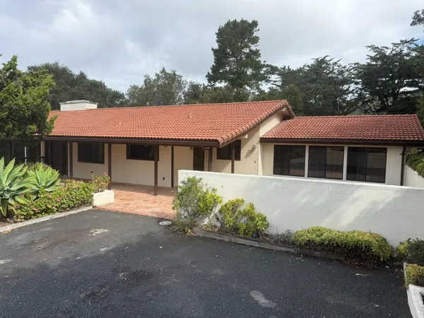 a front view of a house with a garden and parking