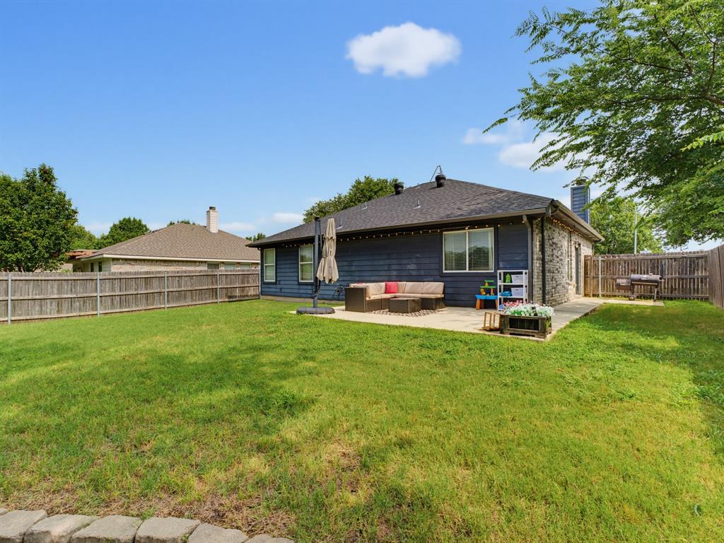 600 Stirling Road Rhome, TX 76078 - Photo 31 of 38 Spacious backyard featuring a large grass lawn, a concrete patio, and a privacy fence
