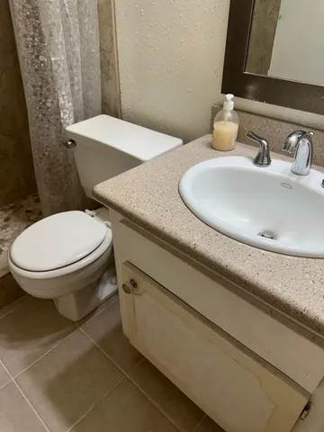 a bathroom with a granite countertop toilet sink and mirror