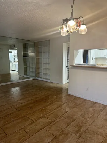 a view of a livingroom with a chandelier fan and kitchen view