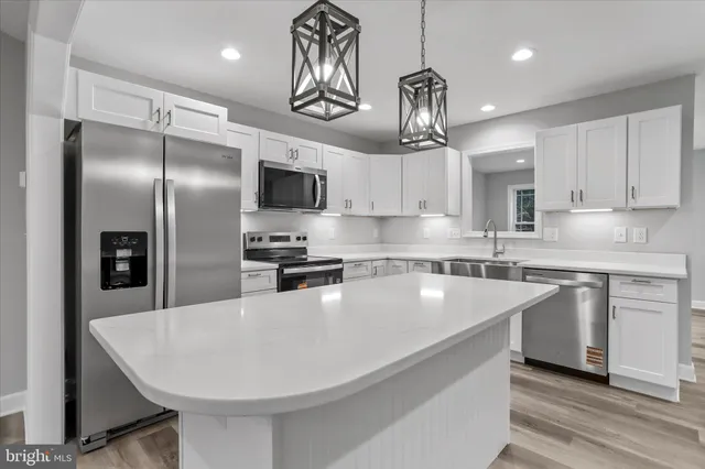 a kitchen with kitchen island a sink stainless steel appliances and cabinets