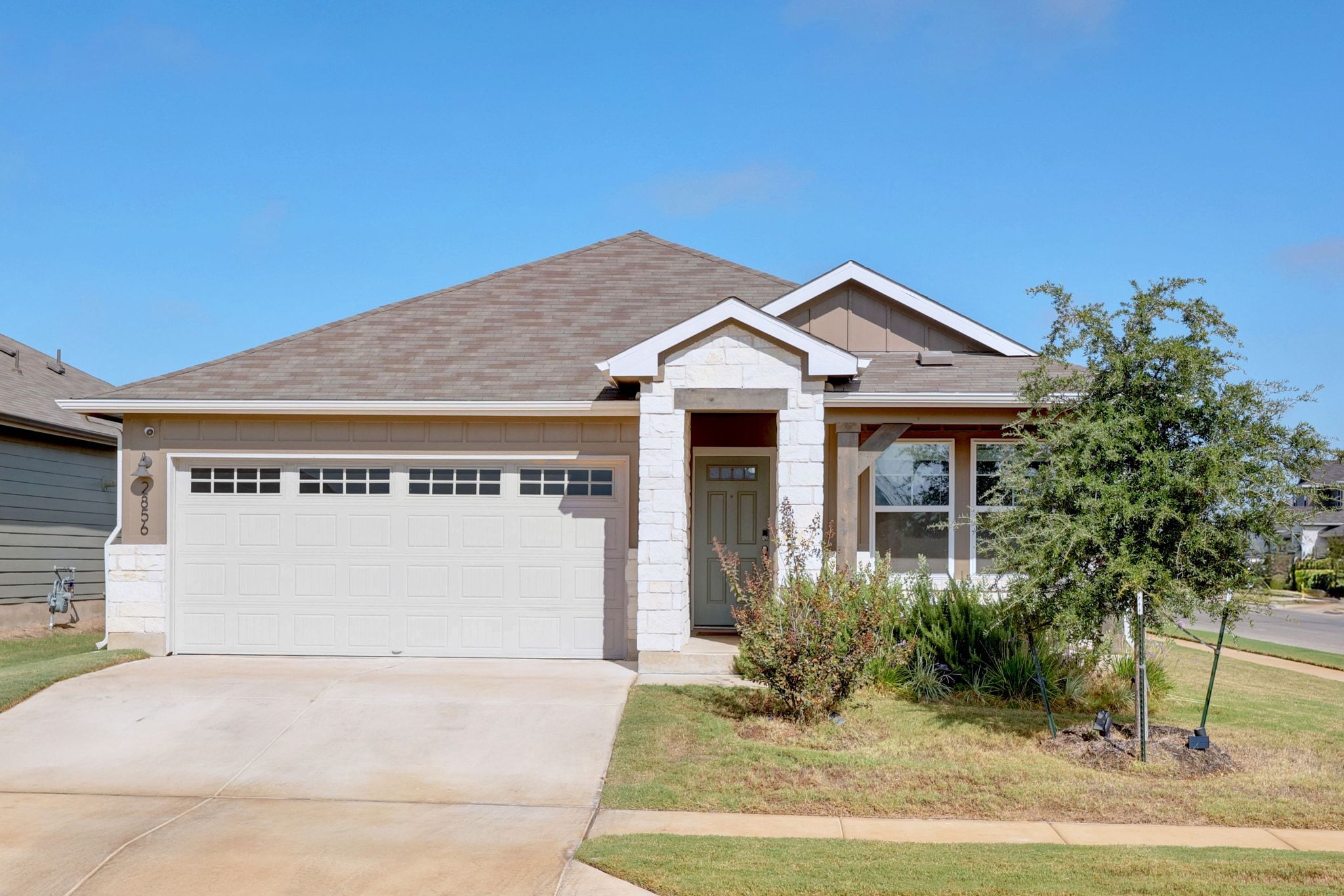 View of front of property with concrete driveway, a garage, stone siding, a shingled roof, and board and batten siding