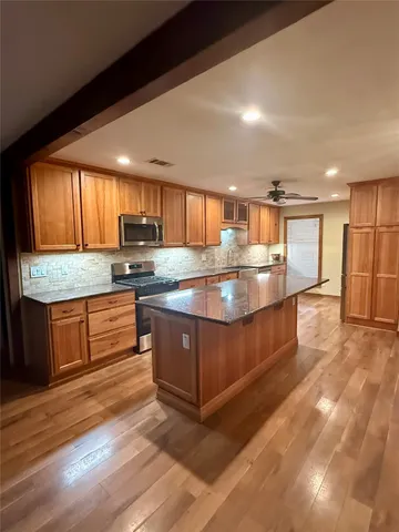 a kitchen with stainless steel appliances granite countertop a stove a sink and a microwave