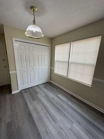 a view of an empty room with a window and wooden floor