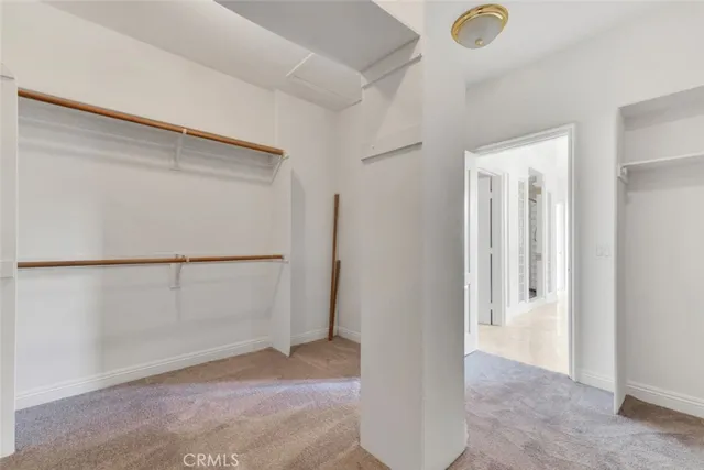 a view of an empty room with wooden floor and kitchen