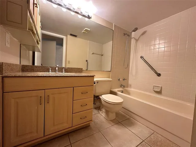 a bathroom with a granite countertop toilet sink and mirror